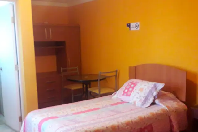 Habitación doble con cama y mesa con sillas junto a la ventana